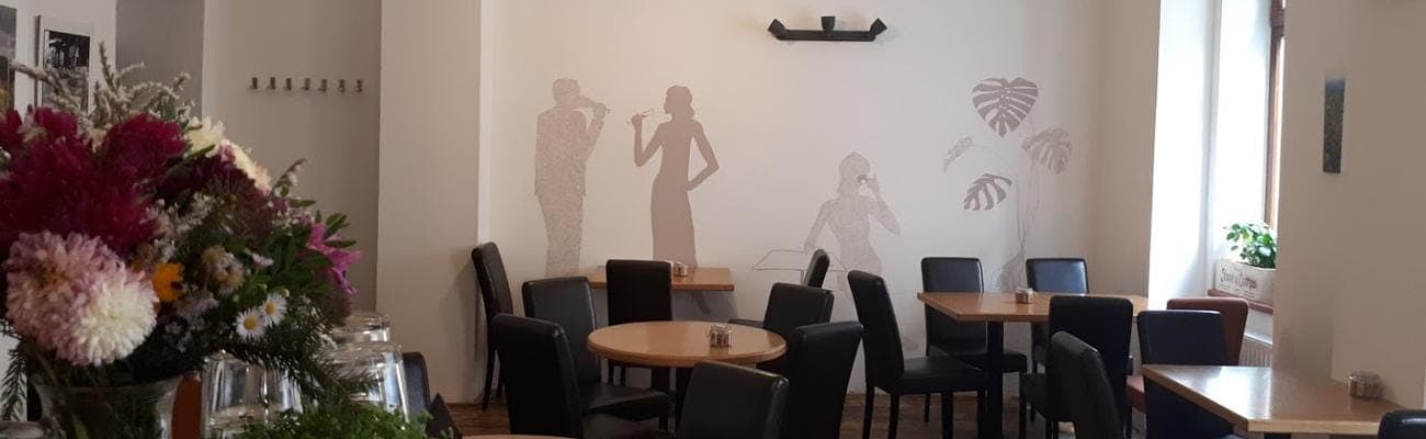 Posezení ve VinCaffé — dřevěné stoly, kytice a nástěnná malba